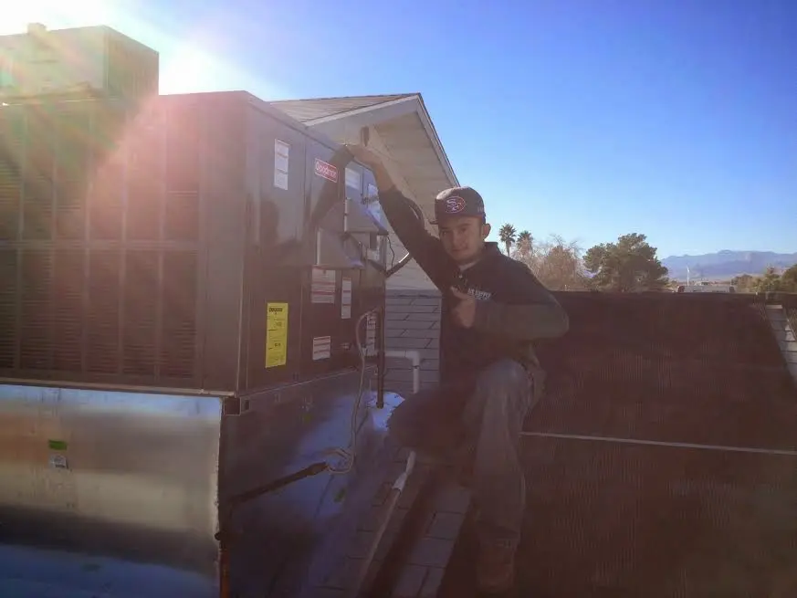 HVAC technician performing AC Tune-Up on a rooftop unit in Hamilton